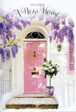 This photograph shows a lovingly styled new-home doorway on the Isle of Dogs, where flowers and colour work together to create a feeling of heartfelt welcome. At the centre stands a pale pink front door, its surface softly painted so the light from nearby Docklands streets seems to glow across it. The surrounding wall is whitewashed, lending a calm, coastal brightness that contrasts beautifully with the pastel tone of the door. Above and around the frame, generous boughs of wisteria droop in cascading clusters of lavender and lilac, forming a loose archway of blossoms. Their dangling flower tassels create a dreamy veil, much like the tranquil atmosphere you find wandering residential lanes near Island Gardens or along the riverside paths. On the doorstep itself sits a grey metal bucket brimming with an abundant bouquet of creamy white roses. The roses are full and plush, their petals layered like soft fabric, each bloom open but not yet fading. Wisps of muted green foliage thread between the flowers, adding gentle volume and a slightly wild, garden-grown touch. A blush-pink ribbon is tied neatly around the bucket, the satin bow echoing the hue of the front door and providing a subtle, romantic flourish. The scene feels intimate and hopeful, as though a local florist has just delivered this arrangement to celebrate a couple collecting their keys or a family starting anew in a townhouse off Manchester Road. The softness of the colours, the suggestion of fragrance from wisteria and roses, and the careful placement of each element combine to express quiet joy, reassurance, and the timeless message of welcome home.